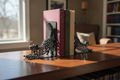 Pair of Aged Copper Voronoi cat bookends on dark wood bookshelf with books
